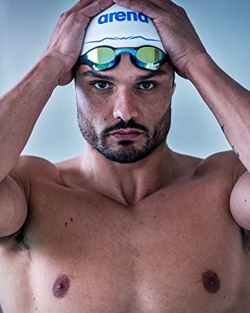 close-up of athlete wearing a white arena aquaforce wave cap and swim goggles at the pool