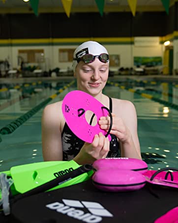 woman athlete in pool with a pile of swim accessories on the side, finger paddles, fins, snorkels