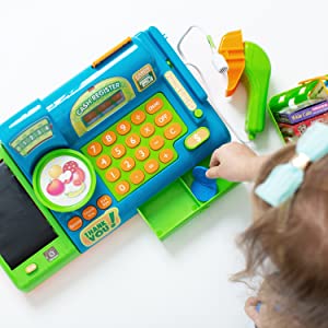 a young girl plays with a blue toy cash register, pretend playing and practicing math skills